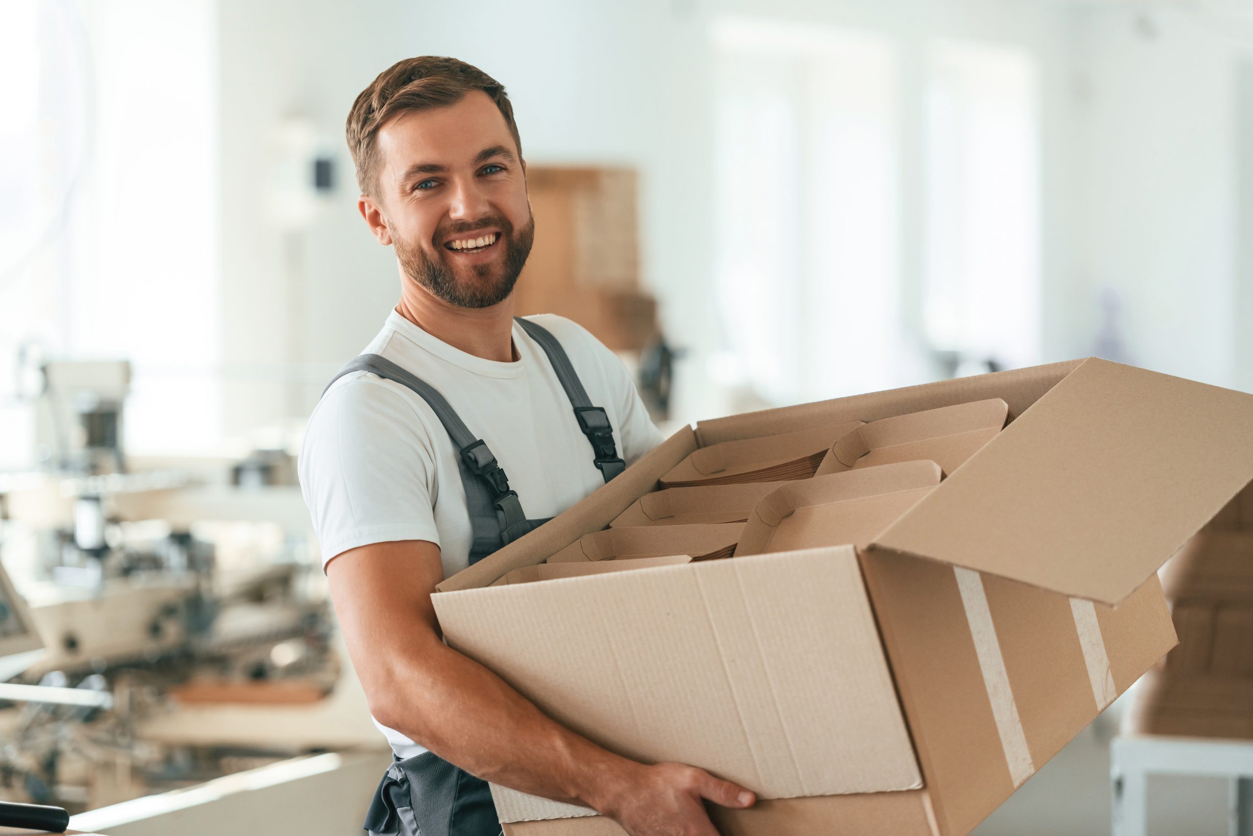 Expert Removals A man holding a cardboard box in a warehouse.