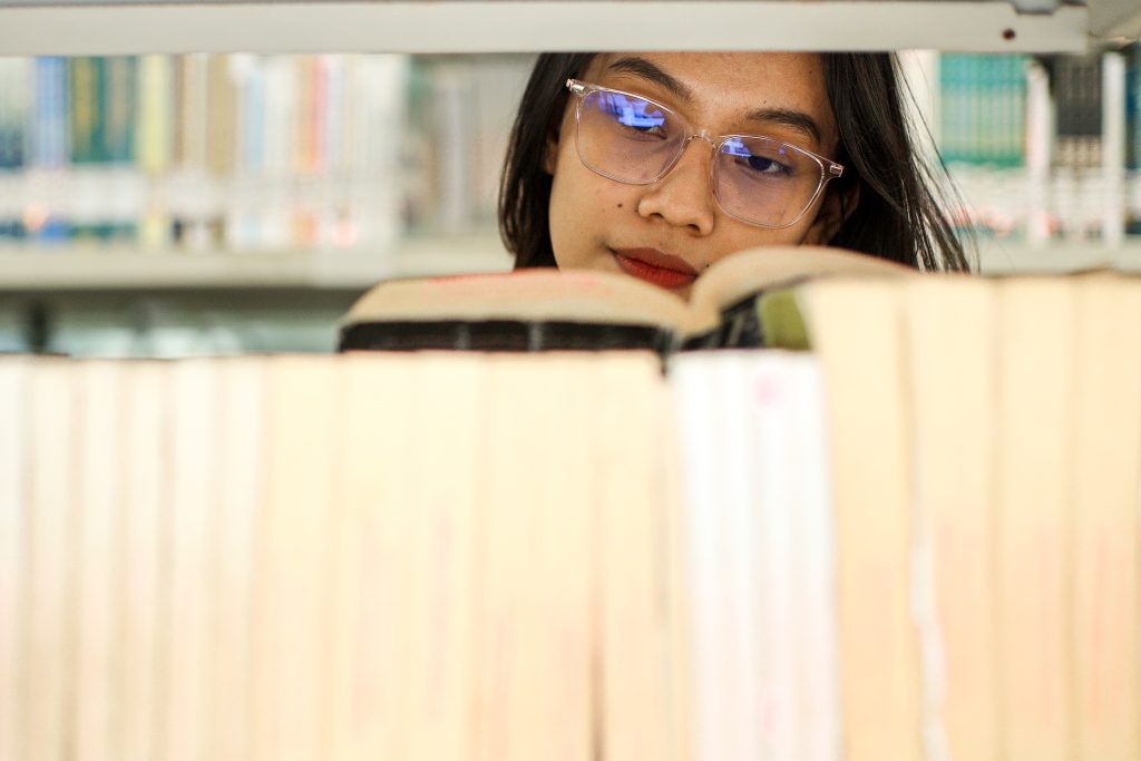 Expert Removals A woman wearing glasses is reading a book in a library.